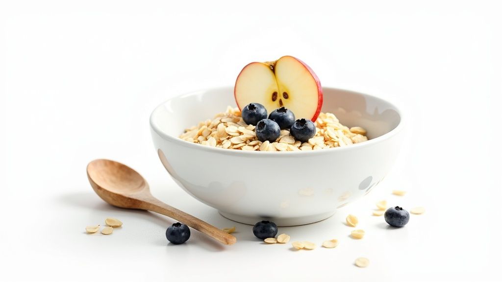 Kauss kaerahelbeid, mustikaid ja õunaviilu valgel taustal, kõrval puidust lusikas.