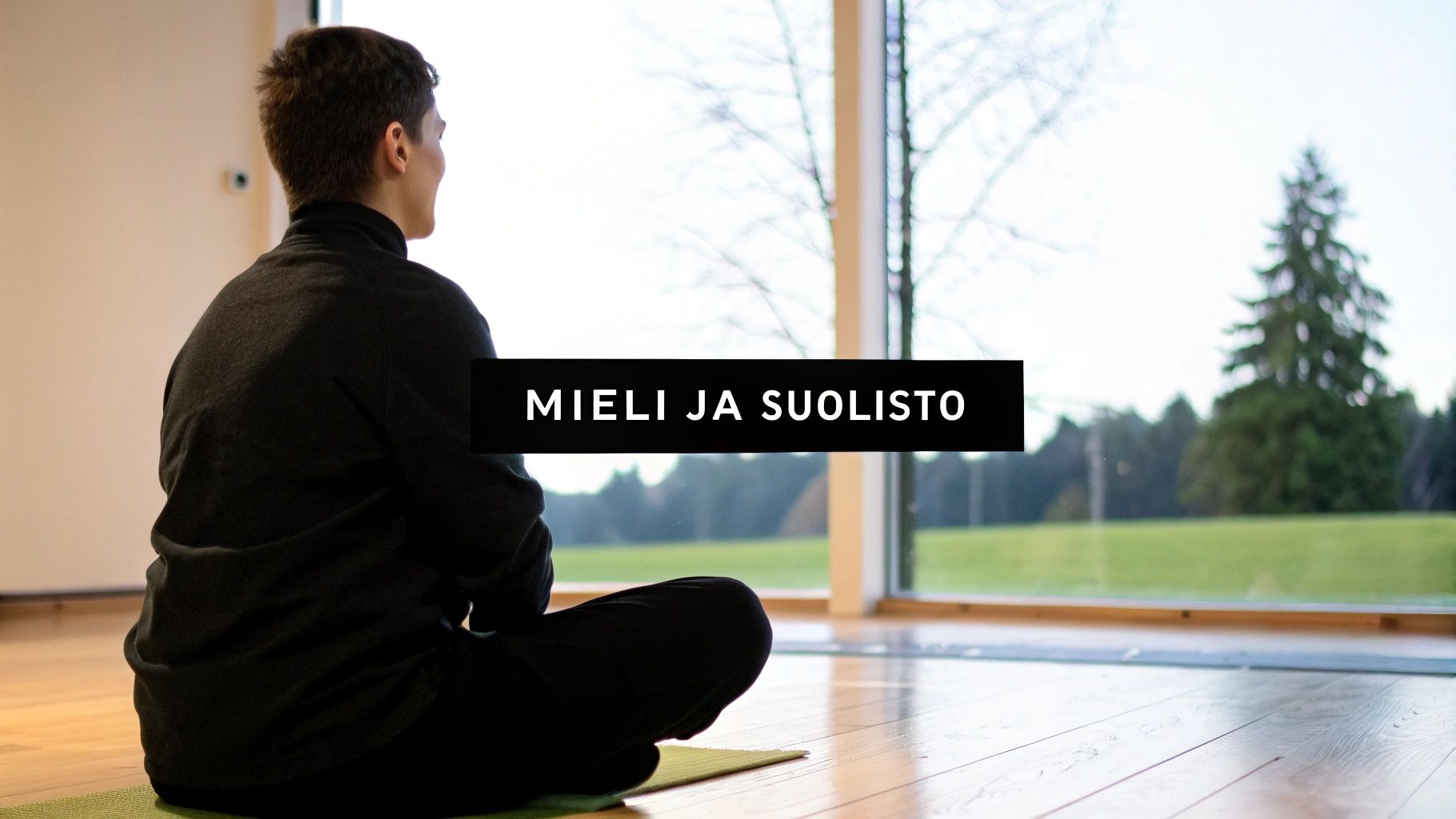 Mies meditoi joogamatolla suuren ikkunan edessä, ulkona näkyy luontoa. Kuvan otsikko: Mieli ja Suolisto.
