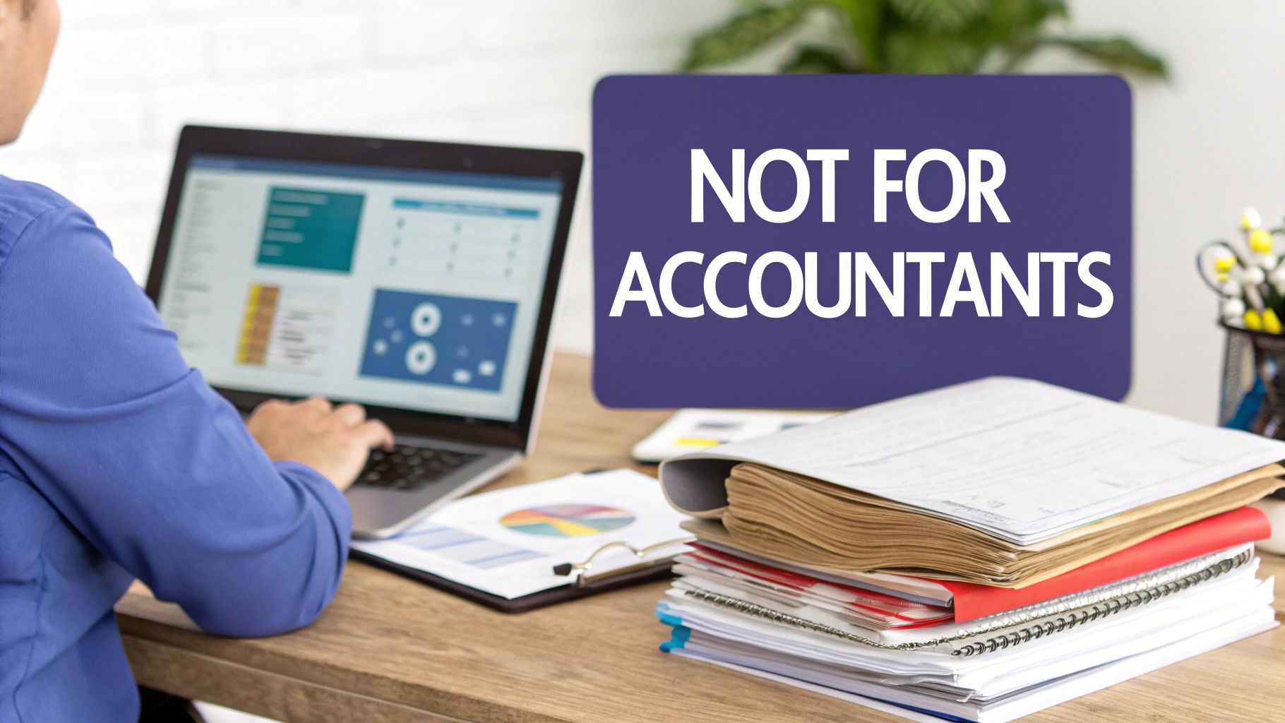 Person using laptop with sign saying not for accountants on desk with documents and notebooks