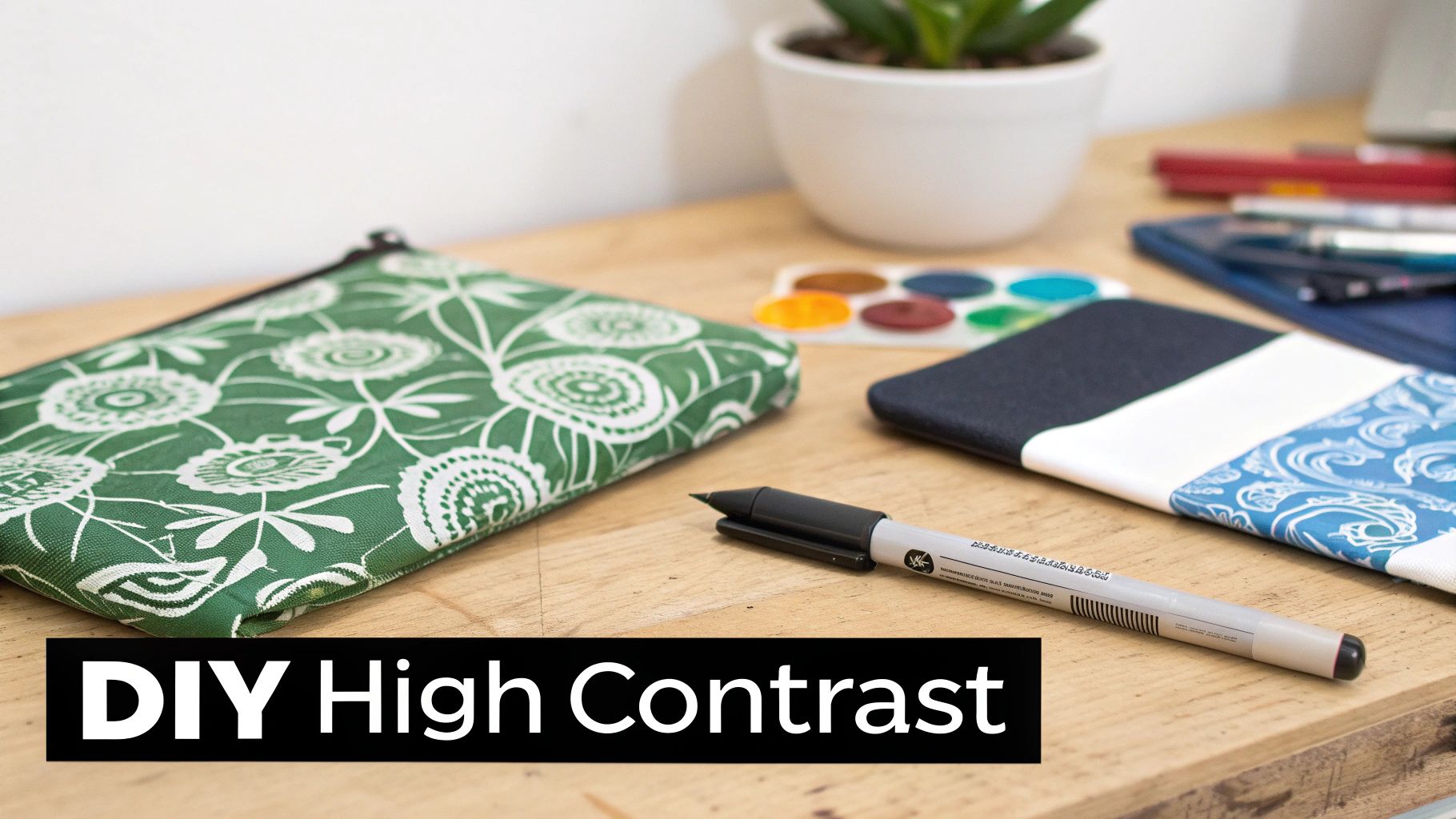 A green floral pouch, a patterned notebook, and a marker on a wooden desk with a DIY High Contrast text overlay.
