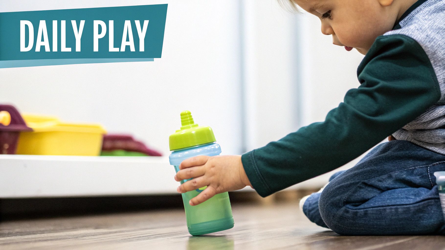 Toddler playing on a wooden floor, holding a vibrant green and blue sippy cup.