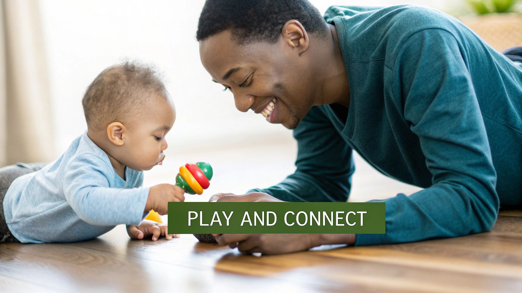 A happy father and baby are playing on a wooden floor with a colorful rattle toy.