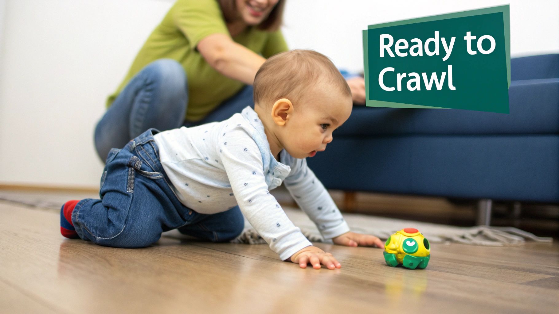 An adorable baby in jeans crawls on a wooden floor, reaching for a toy, with a smiling adult in the background.