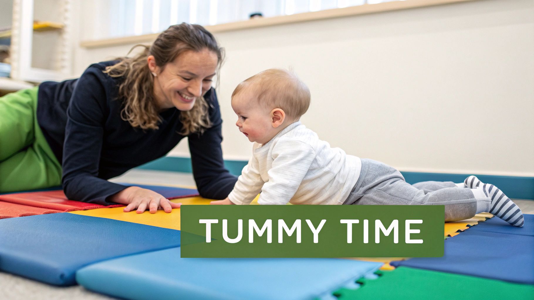 A smiling woman and a baby happily doing tummy time on colorful foam mats.