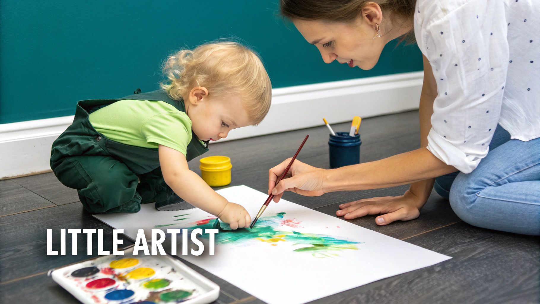 A mother and her toddler paint together on the floor, creating colorful art.