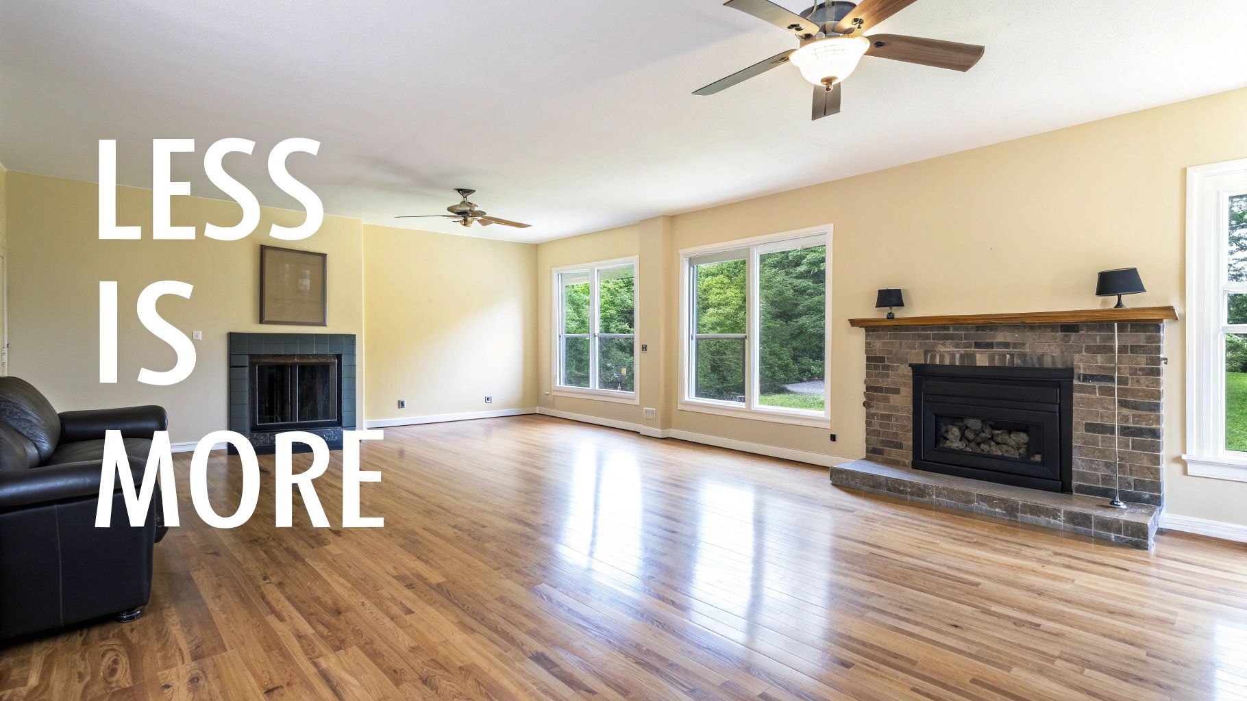 An empty, bright living room with wood floors, two fireplaces, large windows, and "LESS IS MORE" text overlay.