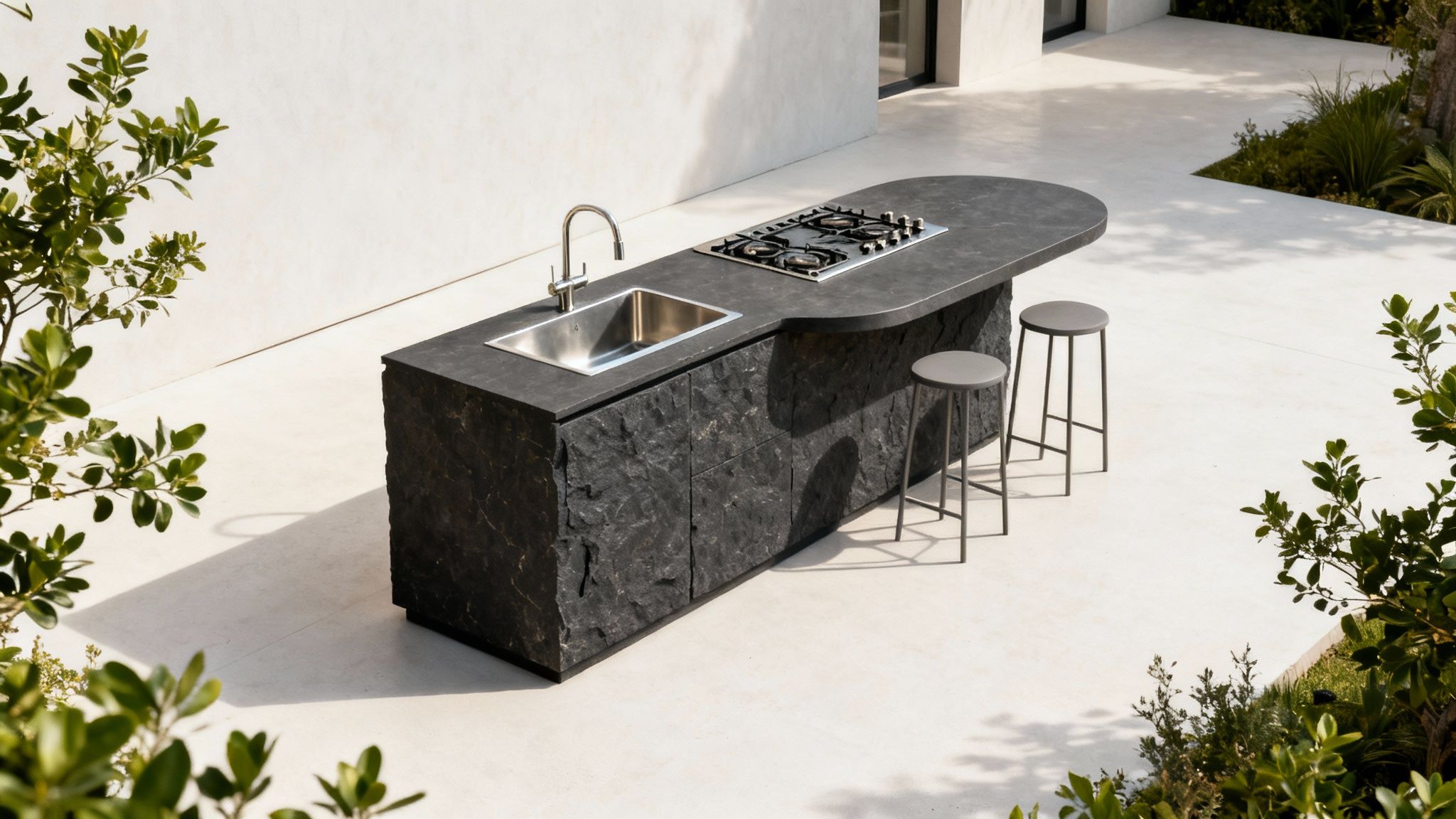 A sleek black outdoor kitchen island with a sink, faucet, and gas hob, surrounded by white flooring and green plants.