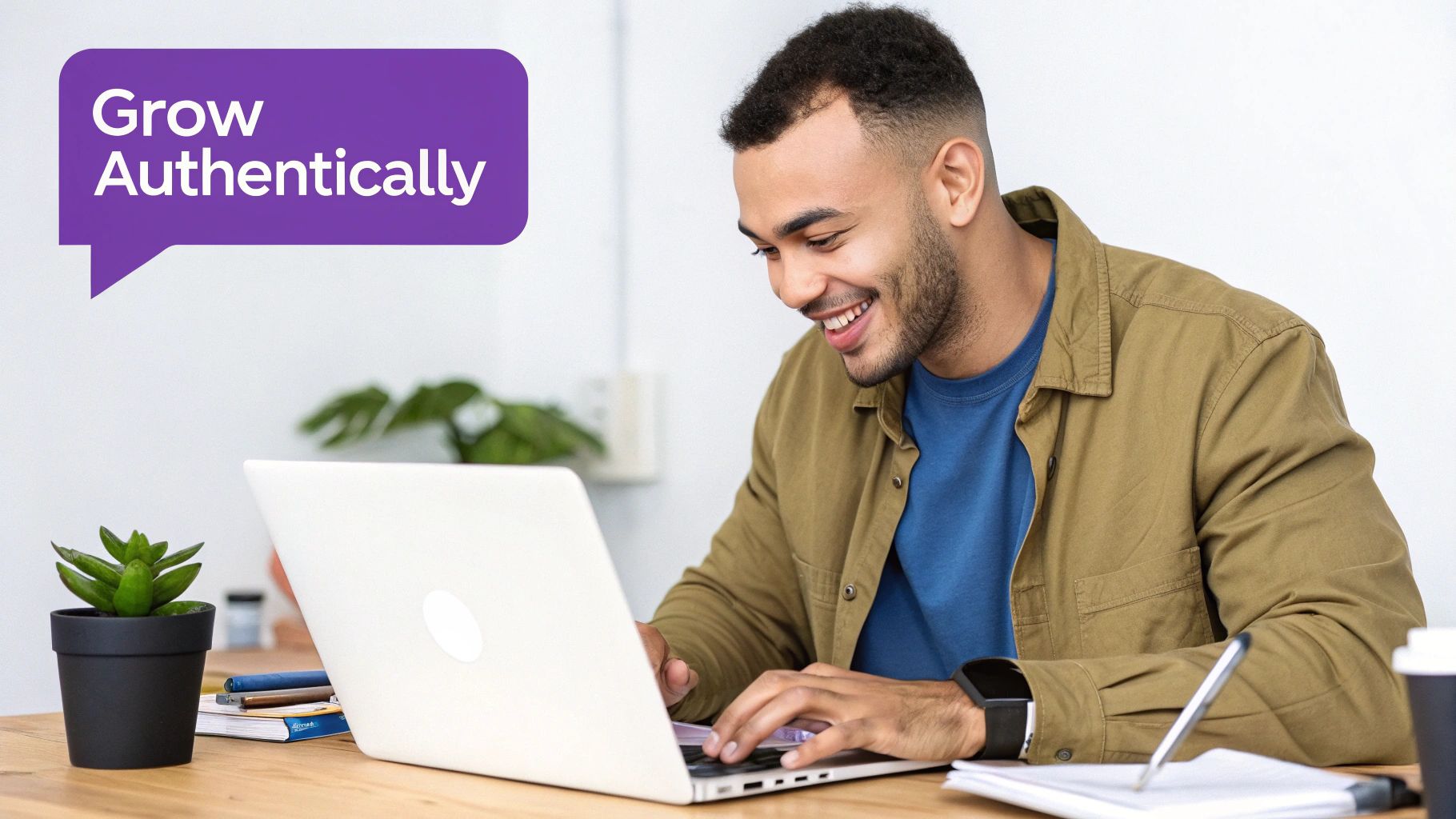 Smiling man working on laptop in modern workspace with motivational text about authentic growth
