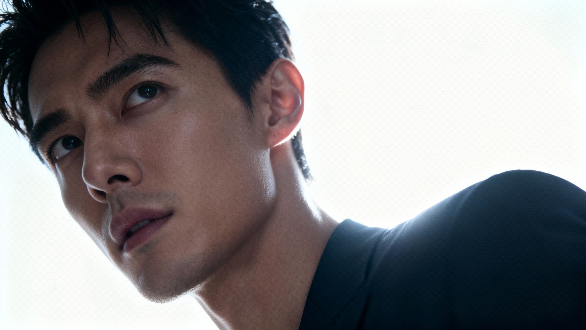 Intense close-up of an Asian man's face, bathed in a bright backlighting glow.