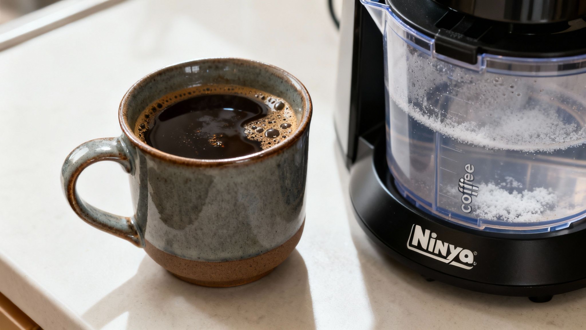 A mug of fresh black coffee sits next to a Ninja coffee maker with a white descaling solution in its reservoir.