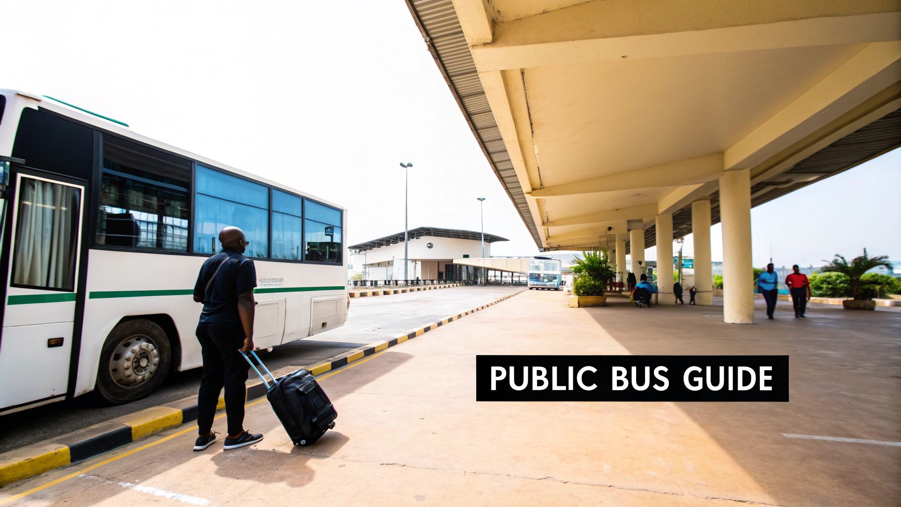 A man pulls a suitcase next to a white and green public bus at an outdoor bus station.