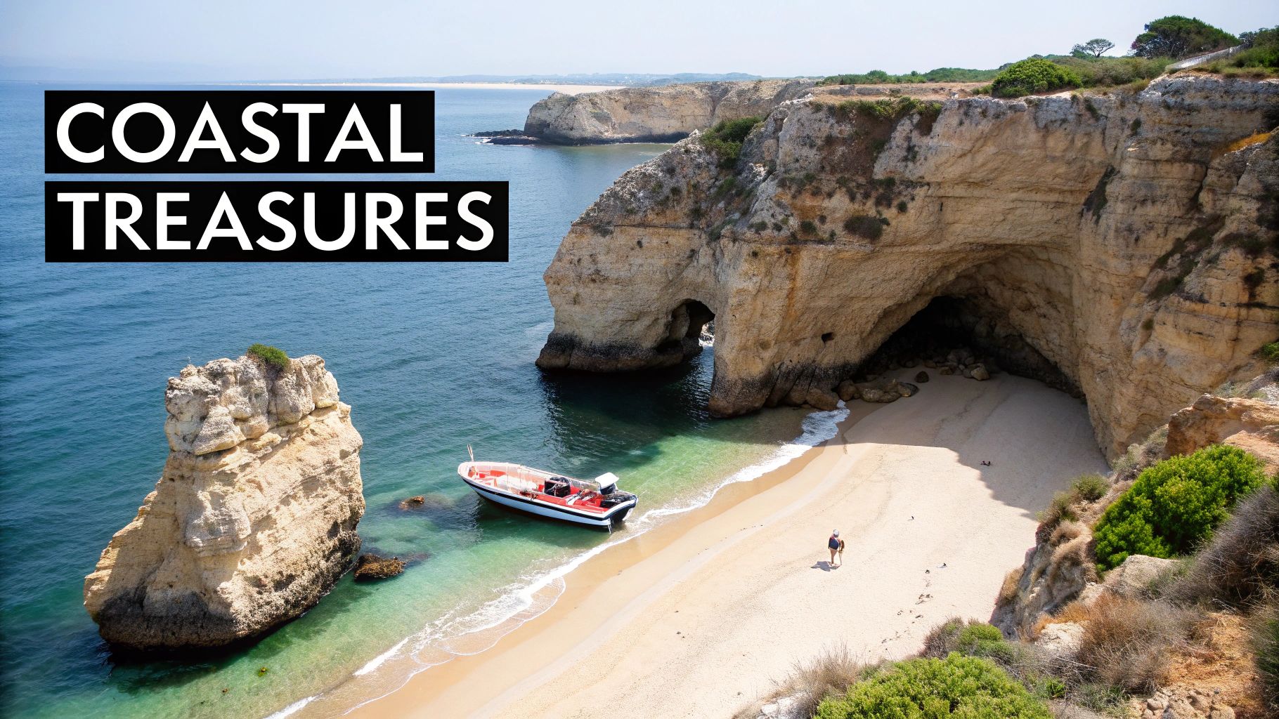 An aerial view of a picturesque beach with a boat, sea caves, and towering cliffs.