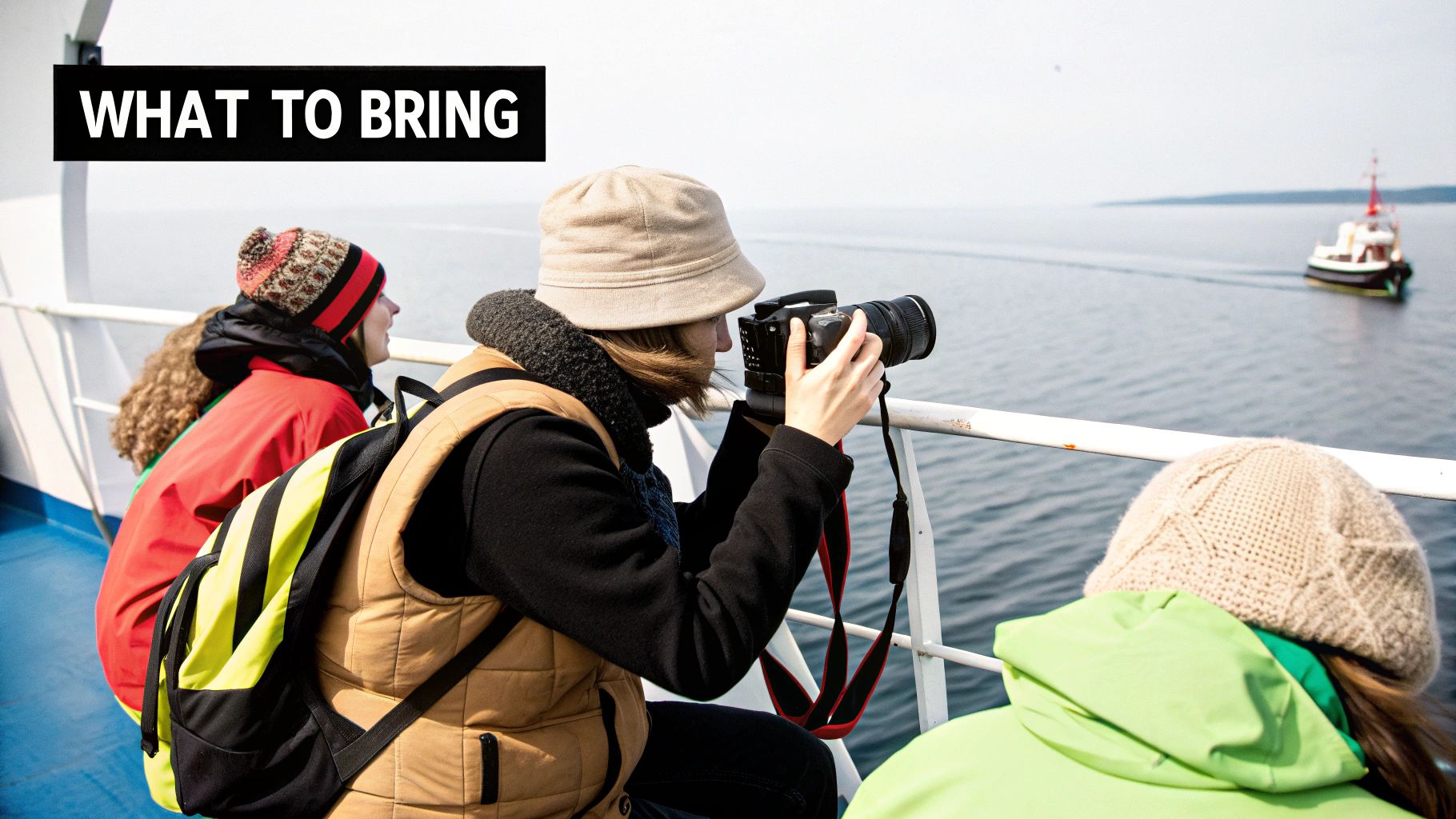 Three tourists on ferry deck photographing ocean during dolphin watching excursion in Algarve