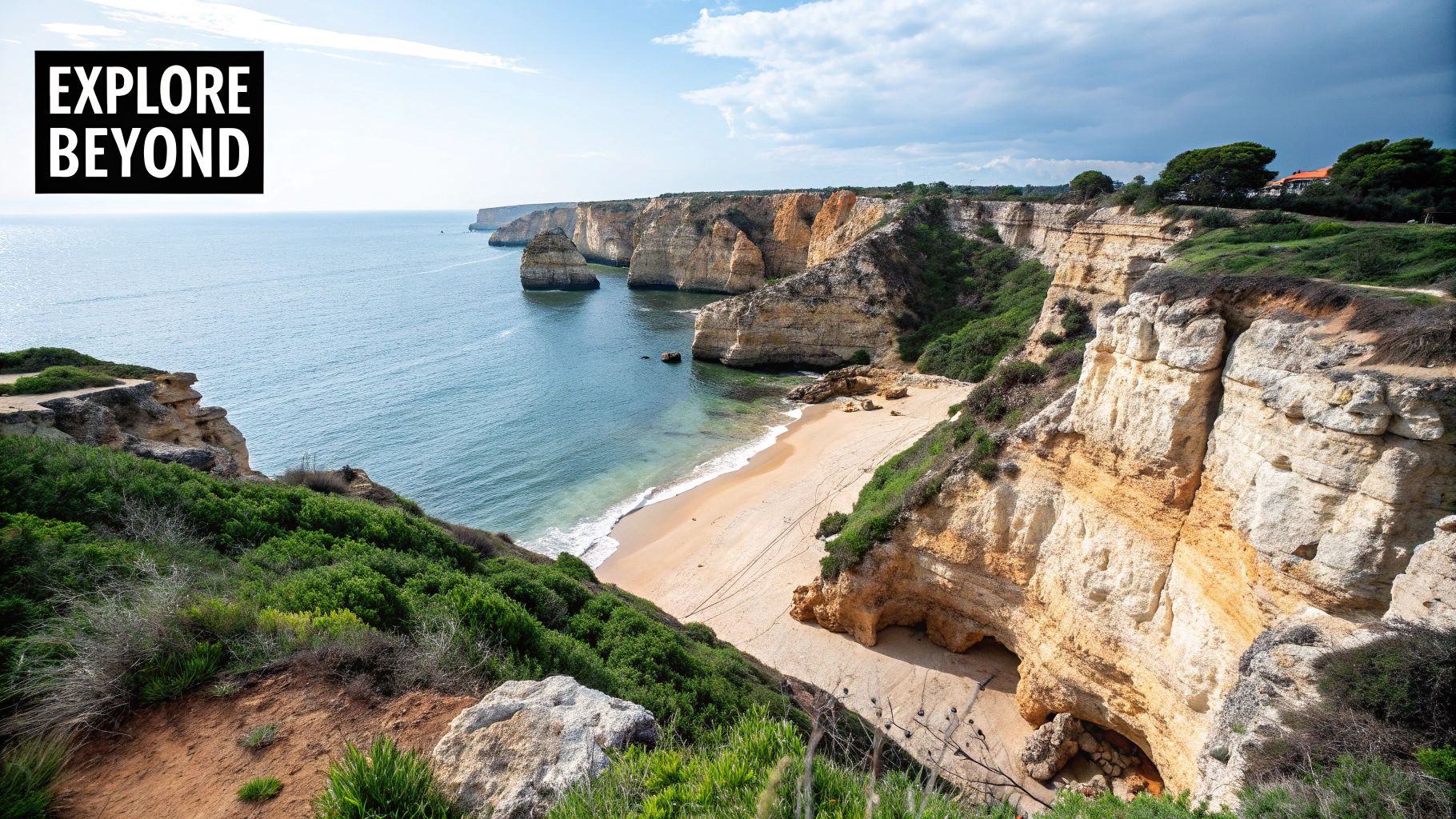 A breathtaking panoramic view of a sandy beach nestled between stunning golden sea cliffs and the blue ocean.