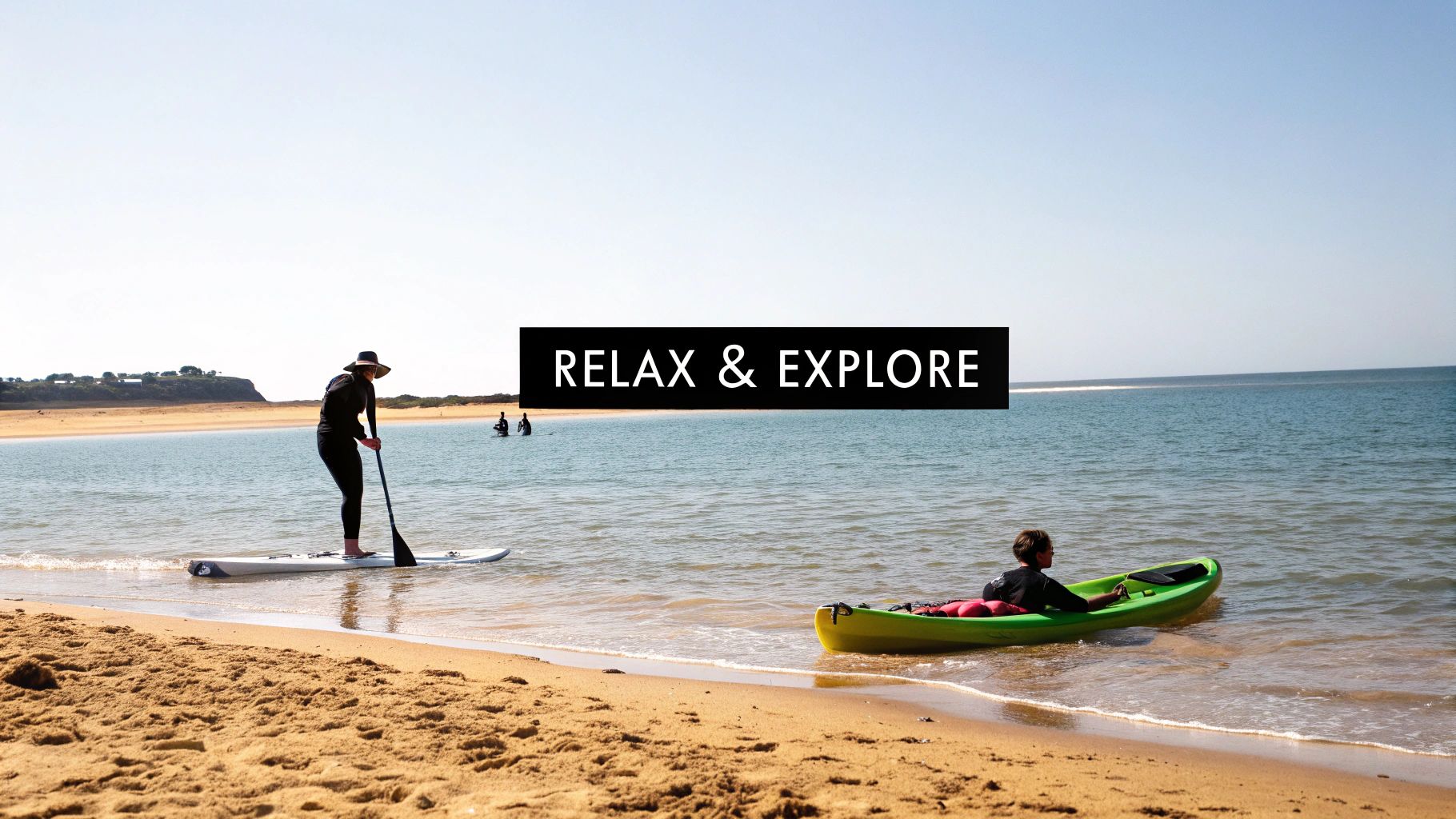 People enjoying water sports on a sunny beach day, with a paddleboarder and a kayaker.
