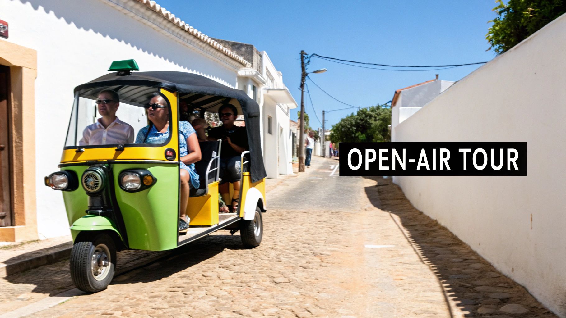 People enjoy an open-air tuk-tuk tour through a sunny, charming European village street.