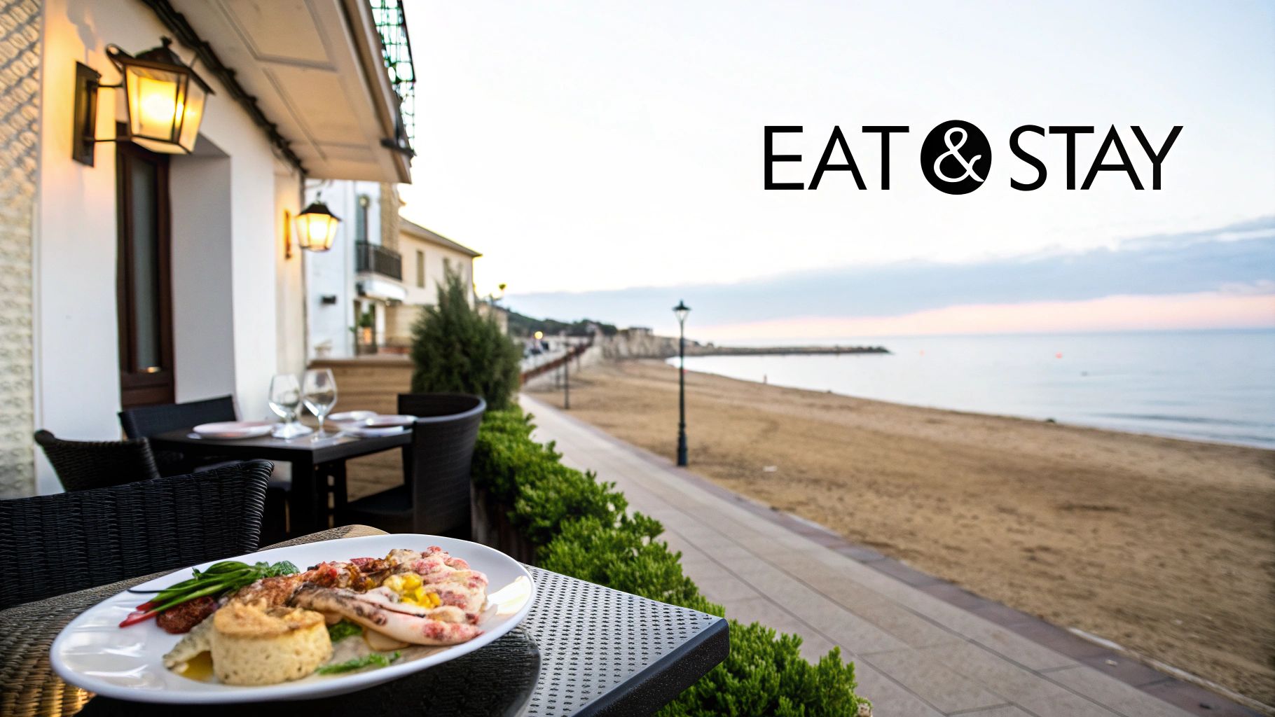 A plate of delicious seafood on an outdoor dining table overlooking a sandy beach at sunset.