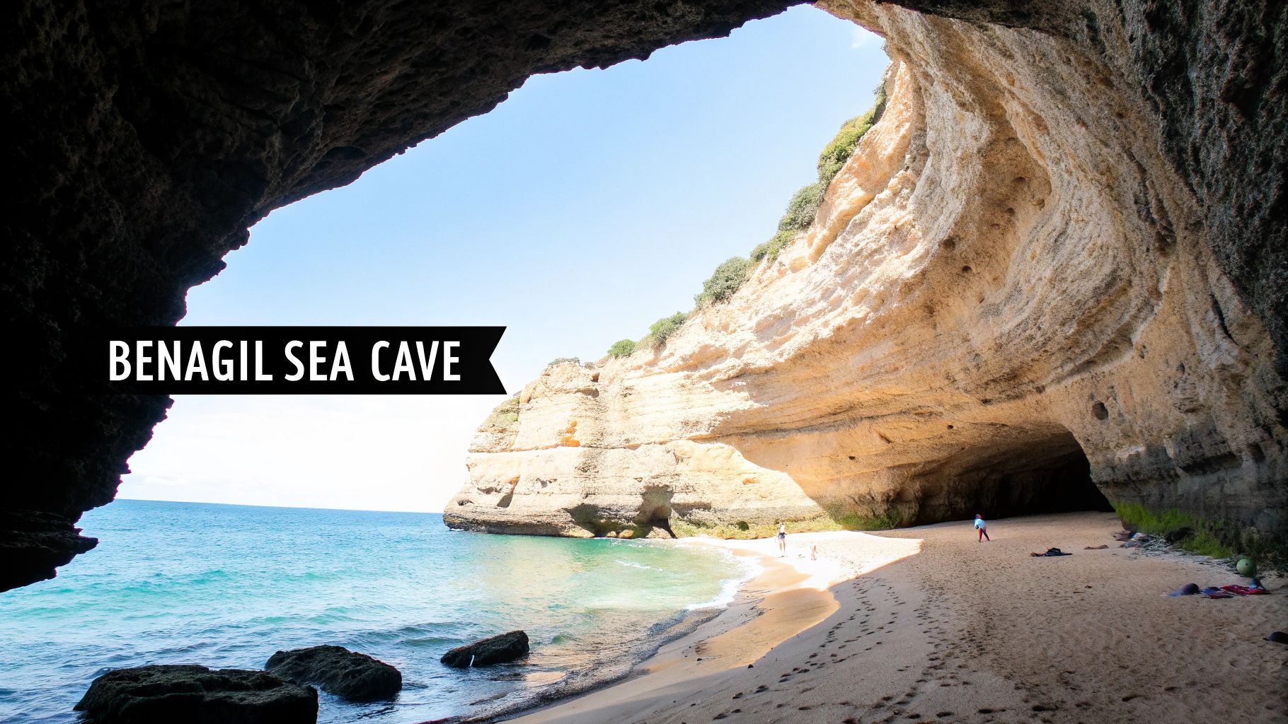 Inside the stunning Benagil Sea Cave in Portugal, showcasing a sandy beach and clear blue ocean.