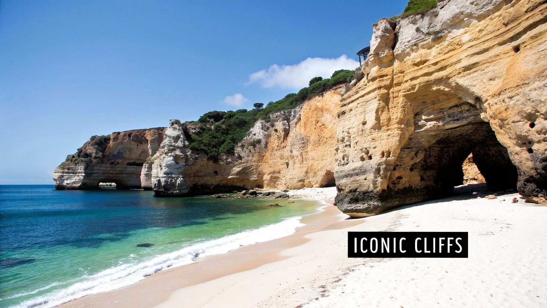 Panoramic view of a sunny white sand beach with turquoise water and majestic golden cliffs featuring sea caves.