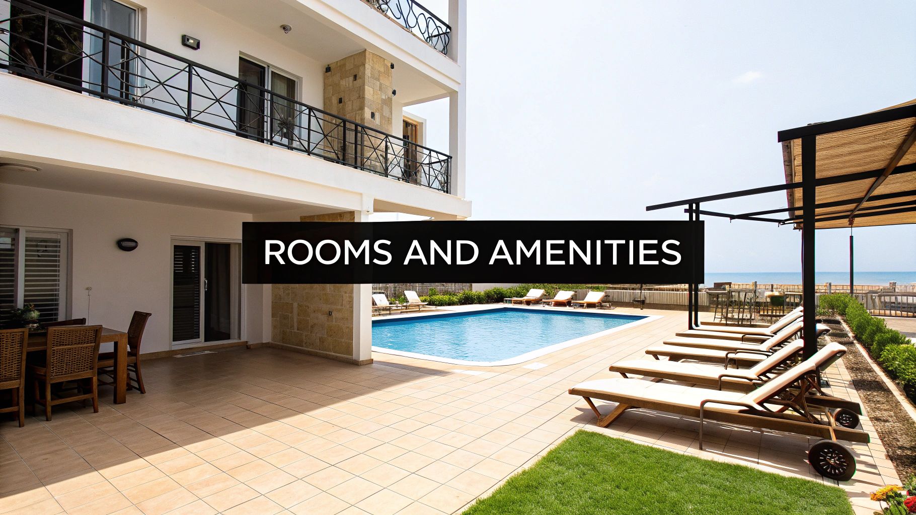 An outdoor view of a hotel with a swimming pool, sun loungers, outdoor dining, and the sea in the background.