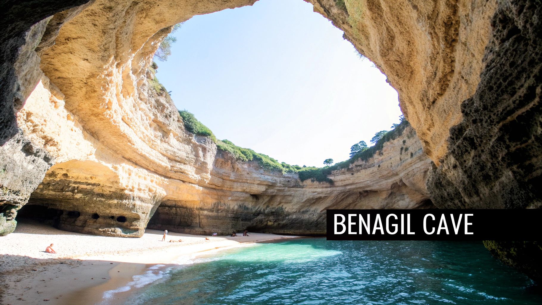 A breathtaking view inside Benagil Cave, Portugal, showing a natural skylight, sandy beach, and turquoise ocean water with people.