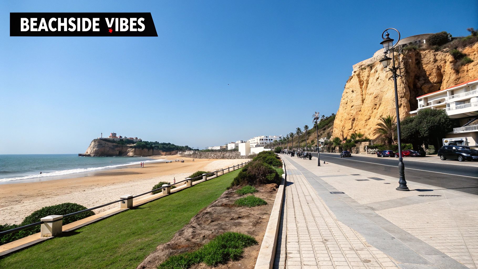 Sunny beach and ocean view with cliffs, a coastal promenade, and a road with cars.
