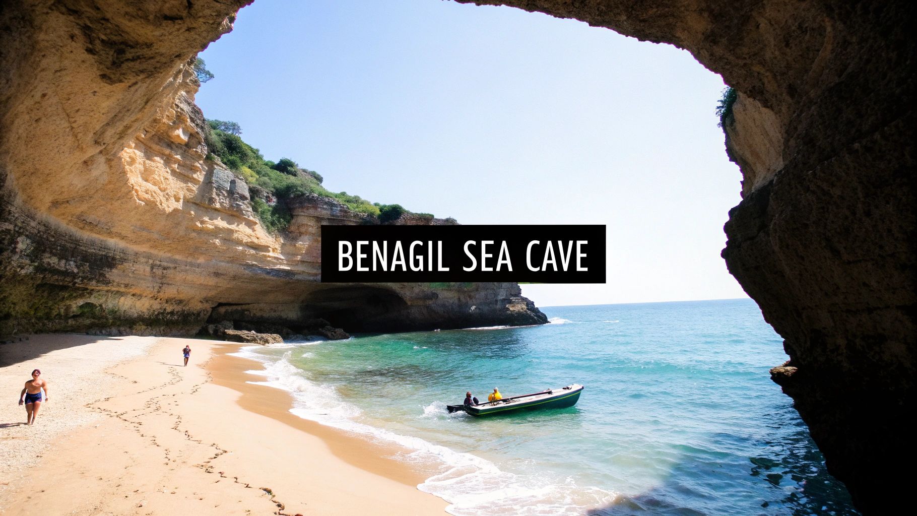 Panoramic view of Benagil Sea Cave entrance with a sandy beach, turquoise water, and a small boat.