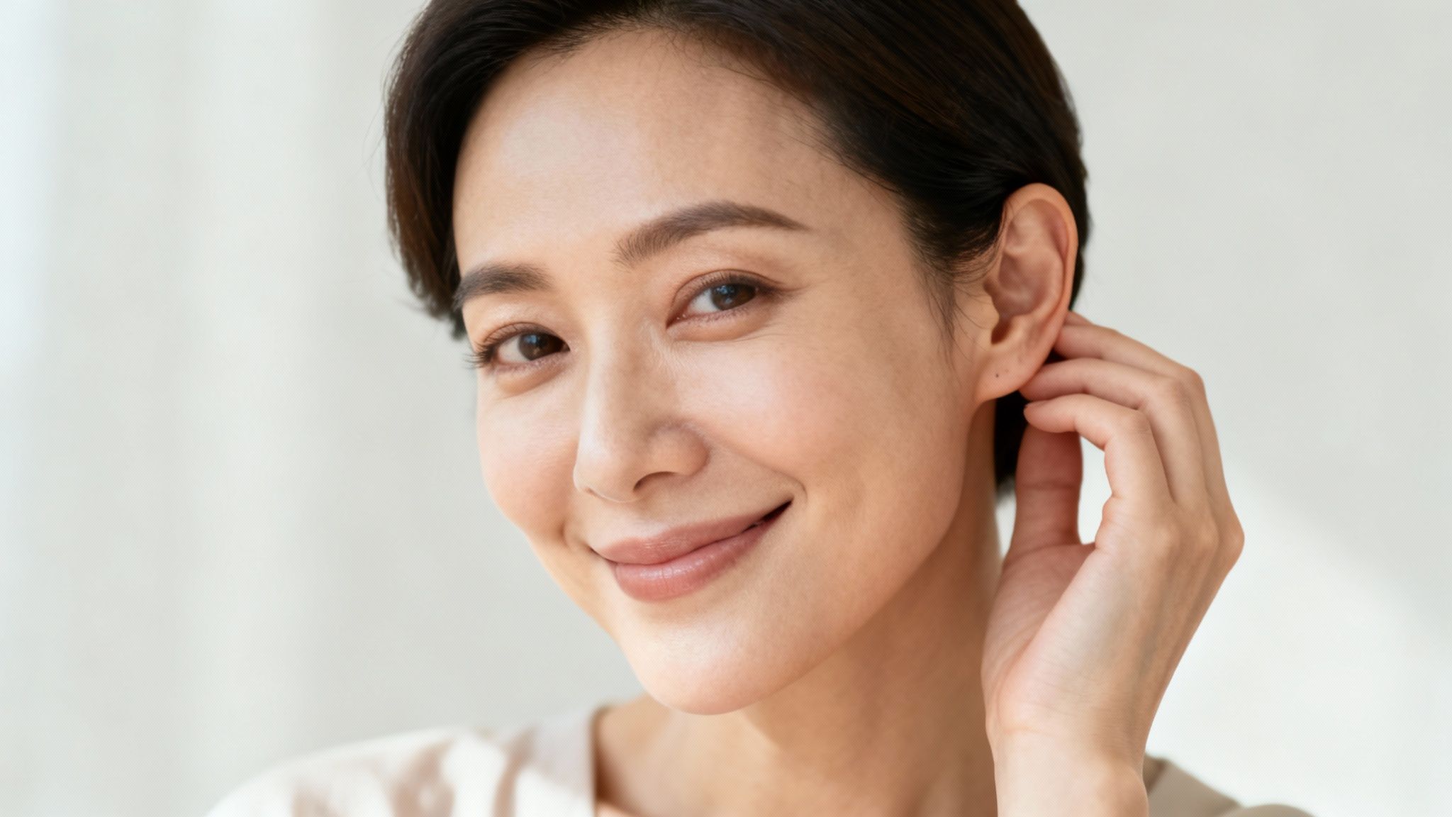 A smiling young woman feeling confident, with her hair styled to show her ears.
