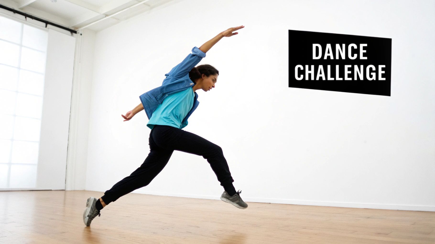 A person in a blue shirt and black pants jumps energetically in a bright studio with a 'DANCE CHALLENGE' sign.