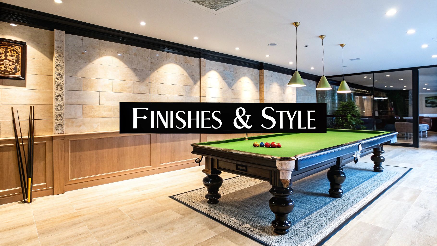 A well-lit indoor leisure room featuring a dark pool table, light-colored tiled walls, and wooden wainscoting.