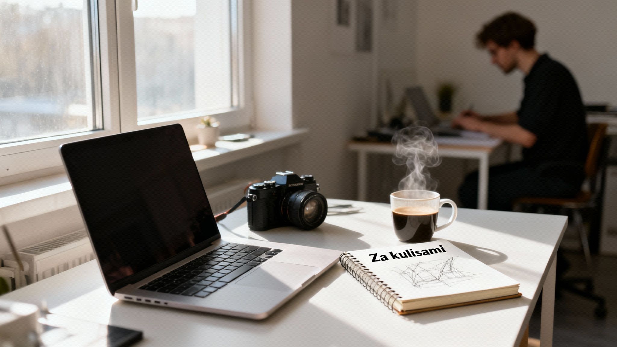 Słoneczne biurko z laptopem, aparatem fotograficznym, filiżanką parującej kawy i notatnikiem.