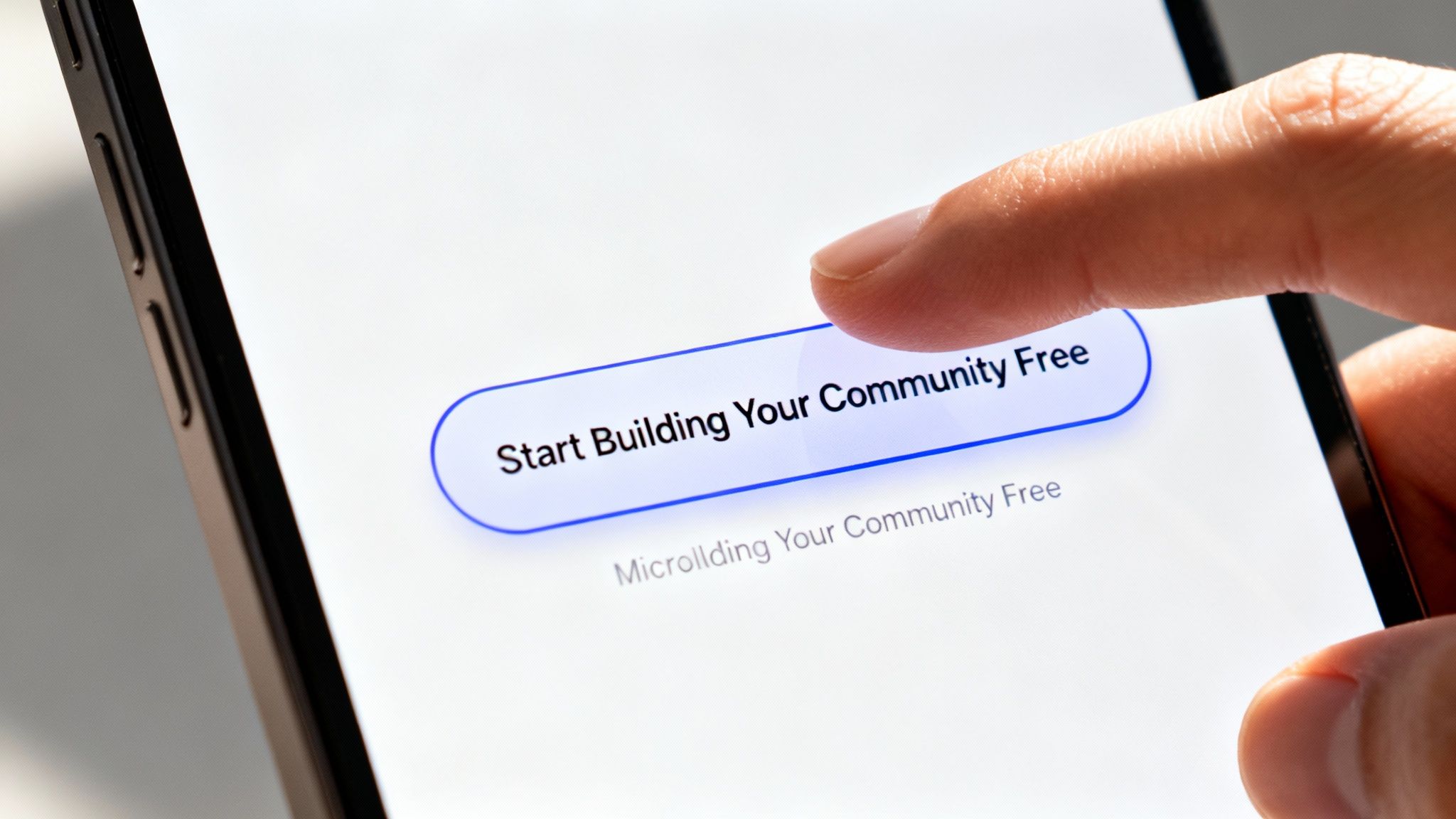 A finger taps a 'Start Building Your Community Free' button on a bright smartphone screen.