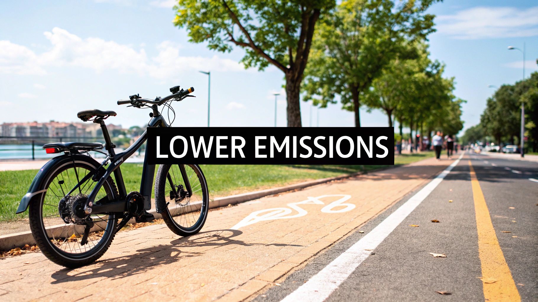A black electric bike is parked on a brick path next to a road, with a 'Lower Emissions' sign.