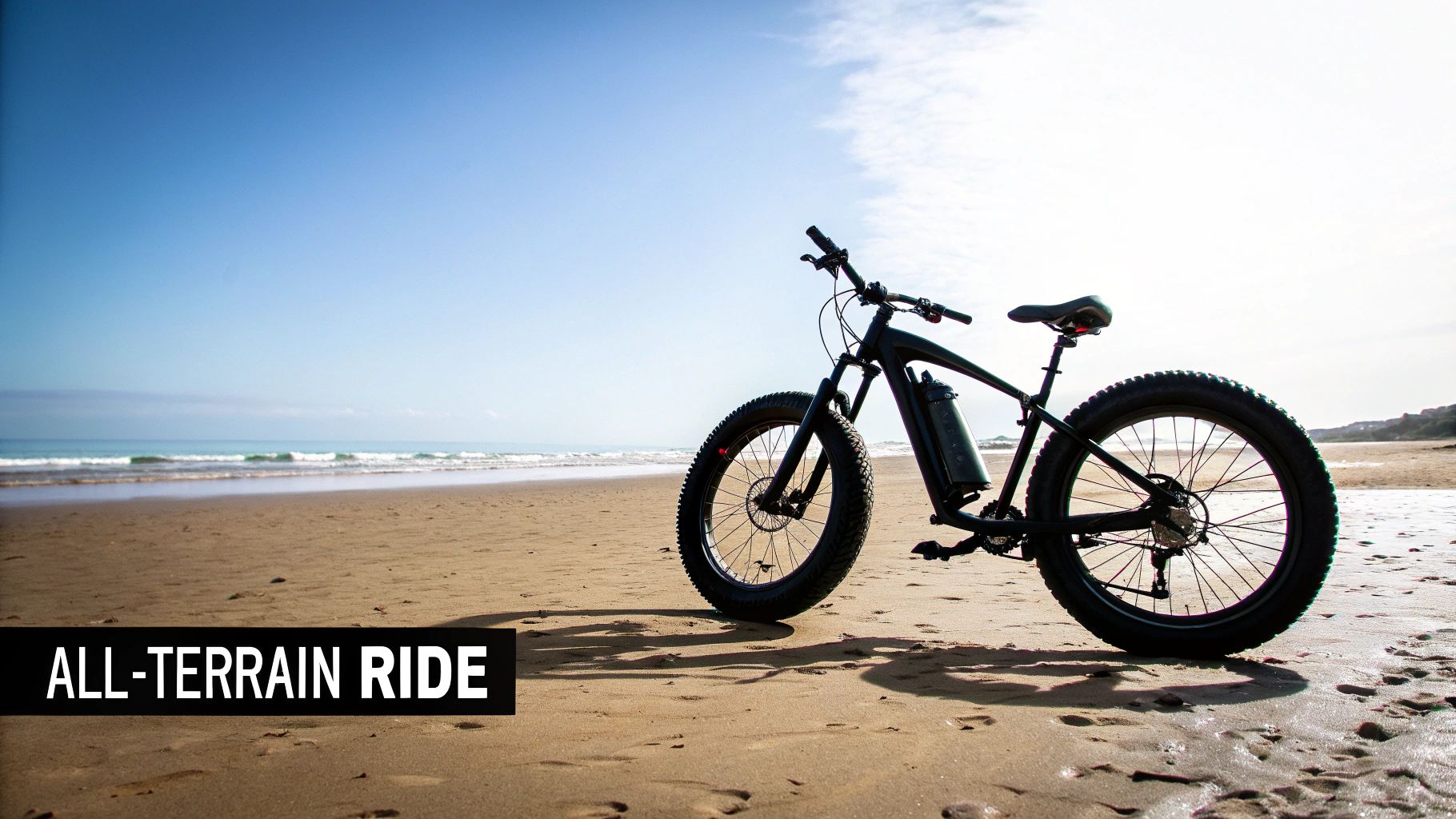 Black fat tire electric bike with wide tires parked on sandy beach near ocean waves