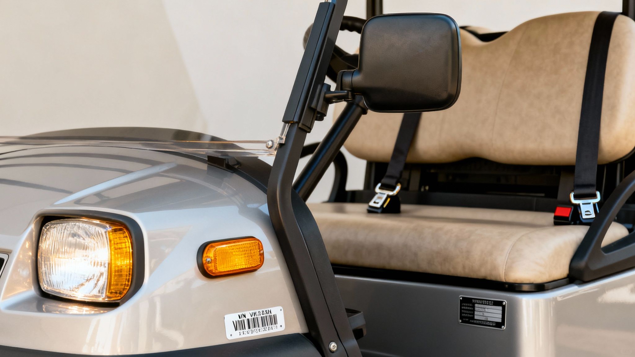 Close-up of a silver street legal golf cart with beige seats, headlights, and turn signals.