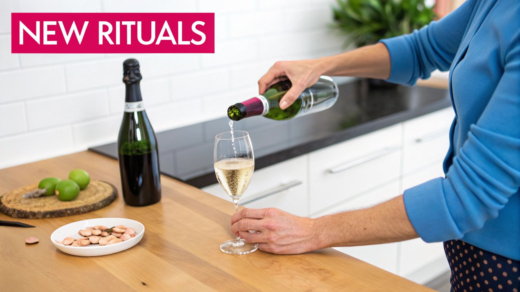 A person pours sparkling wine into a glass on a wooden kitchen counter with limes and snacks.