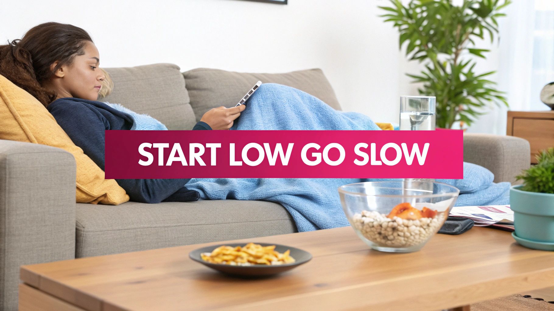 A person relaxes on a couch under a blue blanket, using a tablet, with snacks and a 'START LOW GO SLOW' banner overlaid.