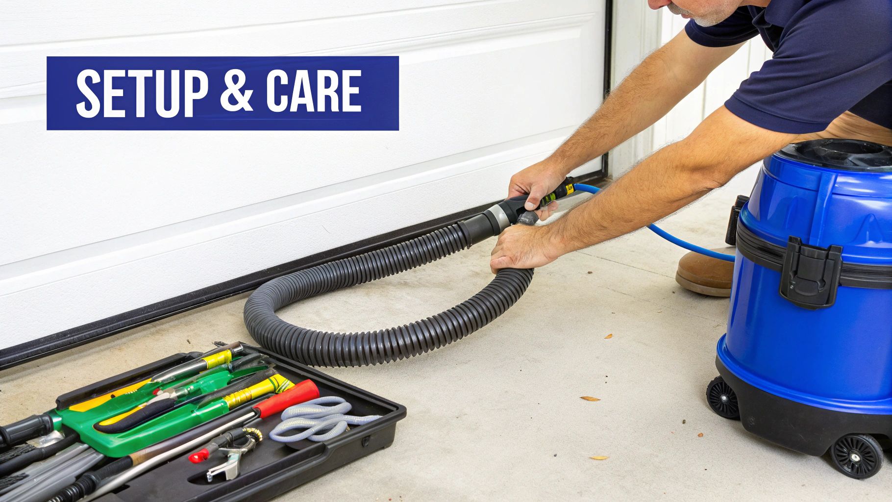 Person connecting a large vacuum hose to a blue shop vac, with tools and a garage door in the background.