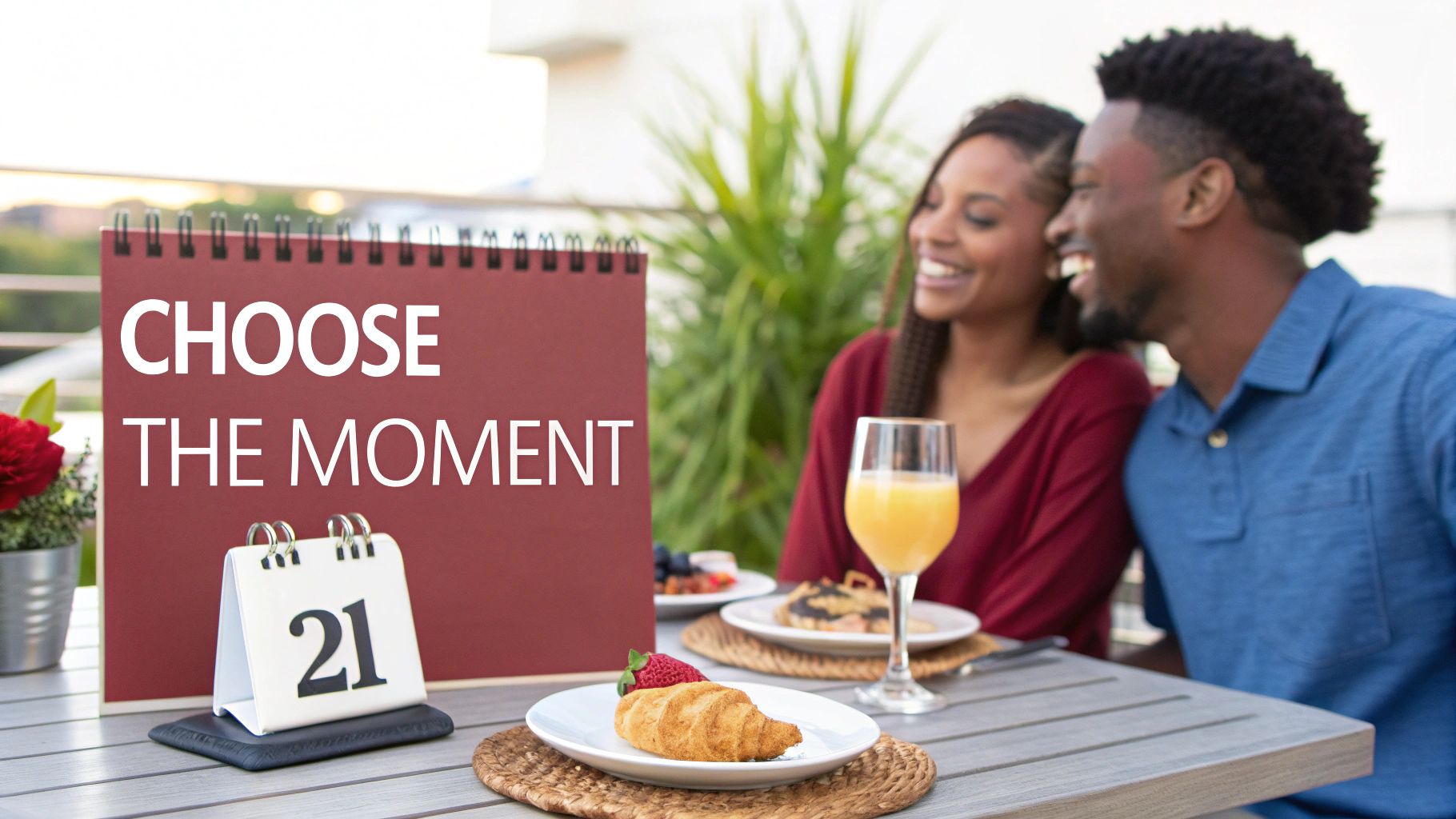 A smiling couple enjoys an outdoor breakfast on a patio with a sign "CHOOSE THE MOMENT" and a calendar showing '21'.