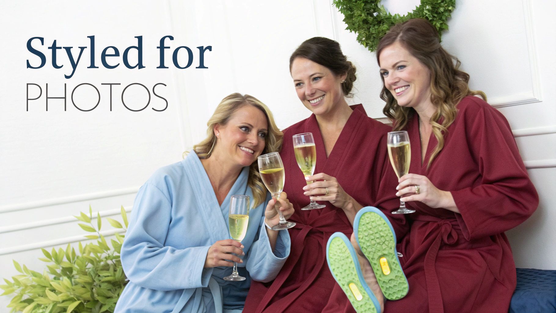 Three smiling women in robes celebrating with champagne, ready for photos.