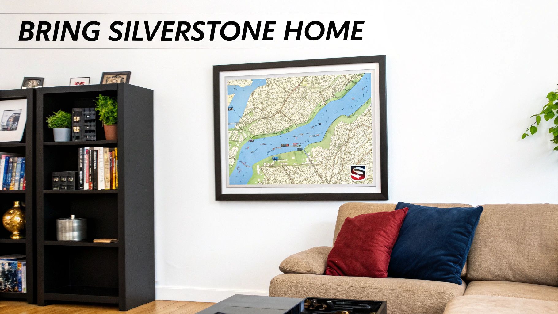 A framed map of the Silverstone circuit hangs on a white wall above a beige couch, alongside a black bookshelf.