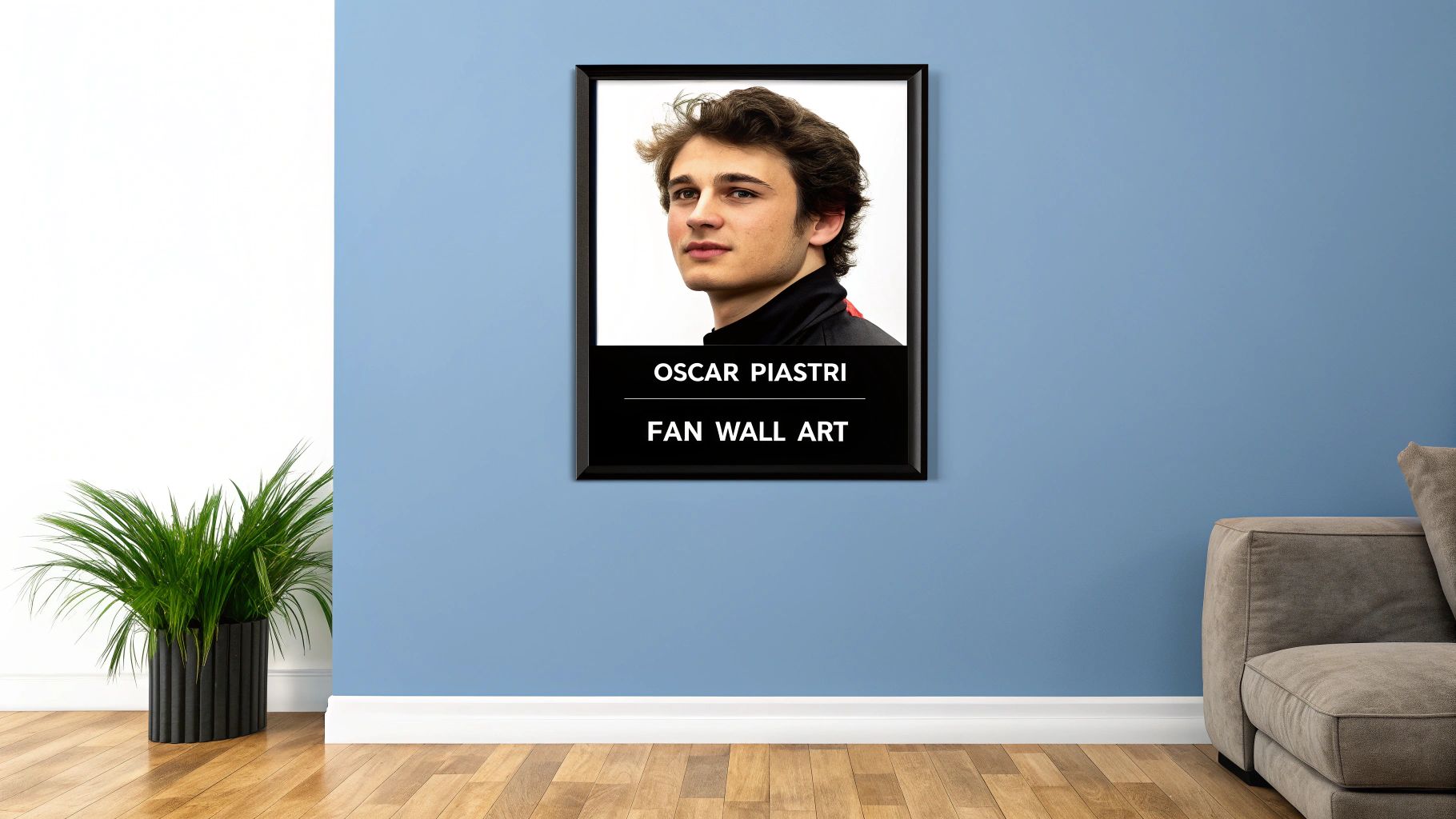 A black-framed picture of Oscar Piastri hangs on a blue wall, next to a green plant and a brown sofa.