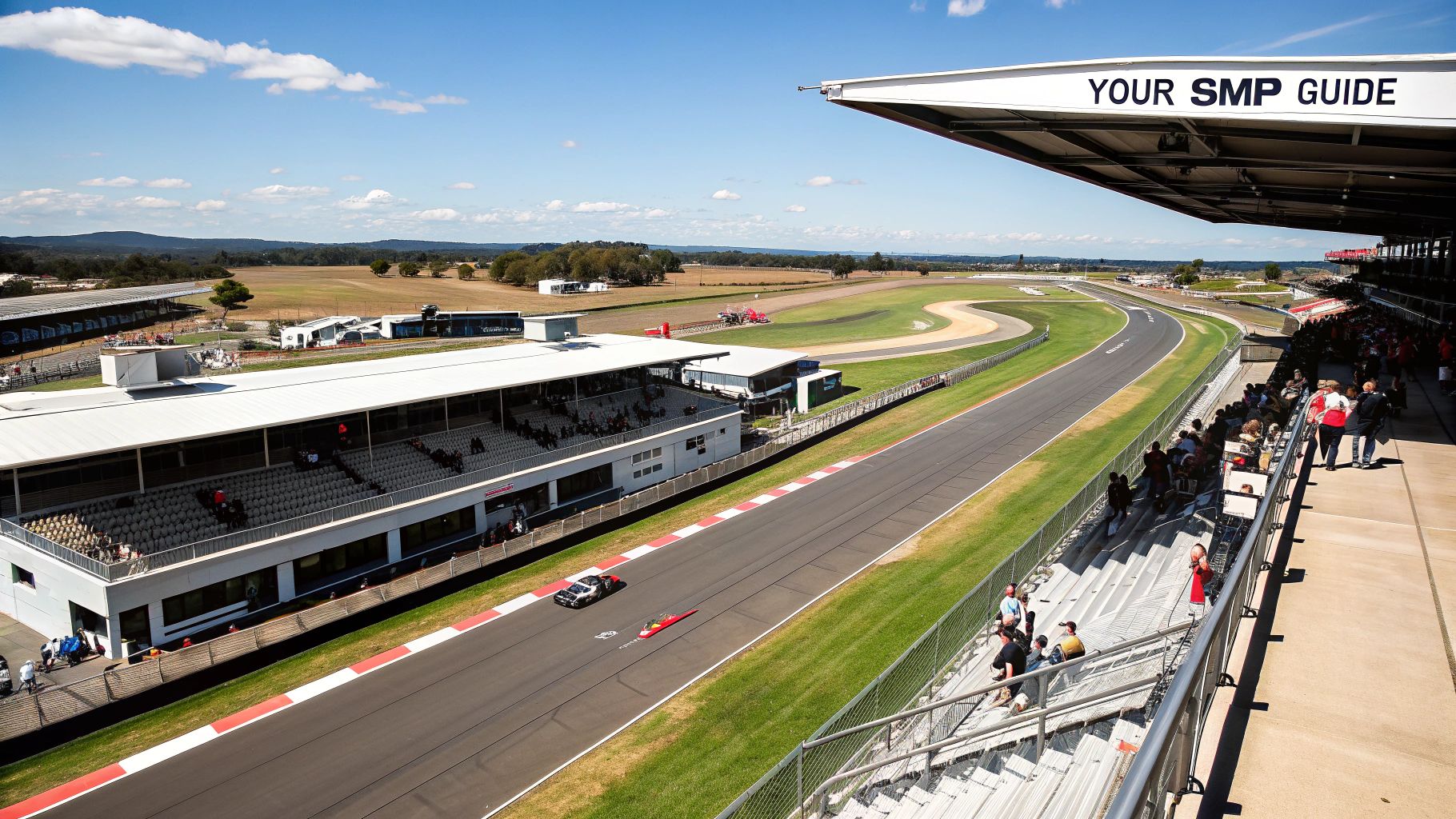 Wide view of Sydney Motorsport Park with race track, grandstands, spectators, and vehicles under a sunny sky.