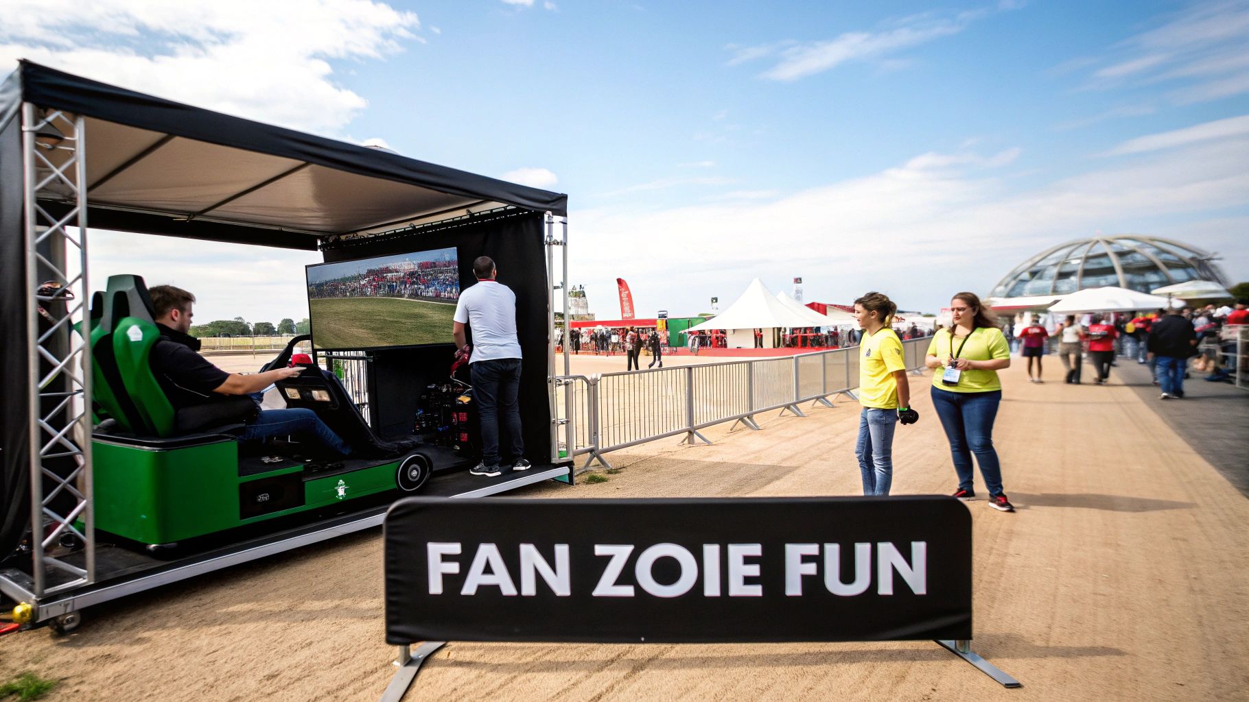 People enjoy an outdoor event with a racing simulator, a large screen, and a 'FAN ZOIE FUN' banner.