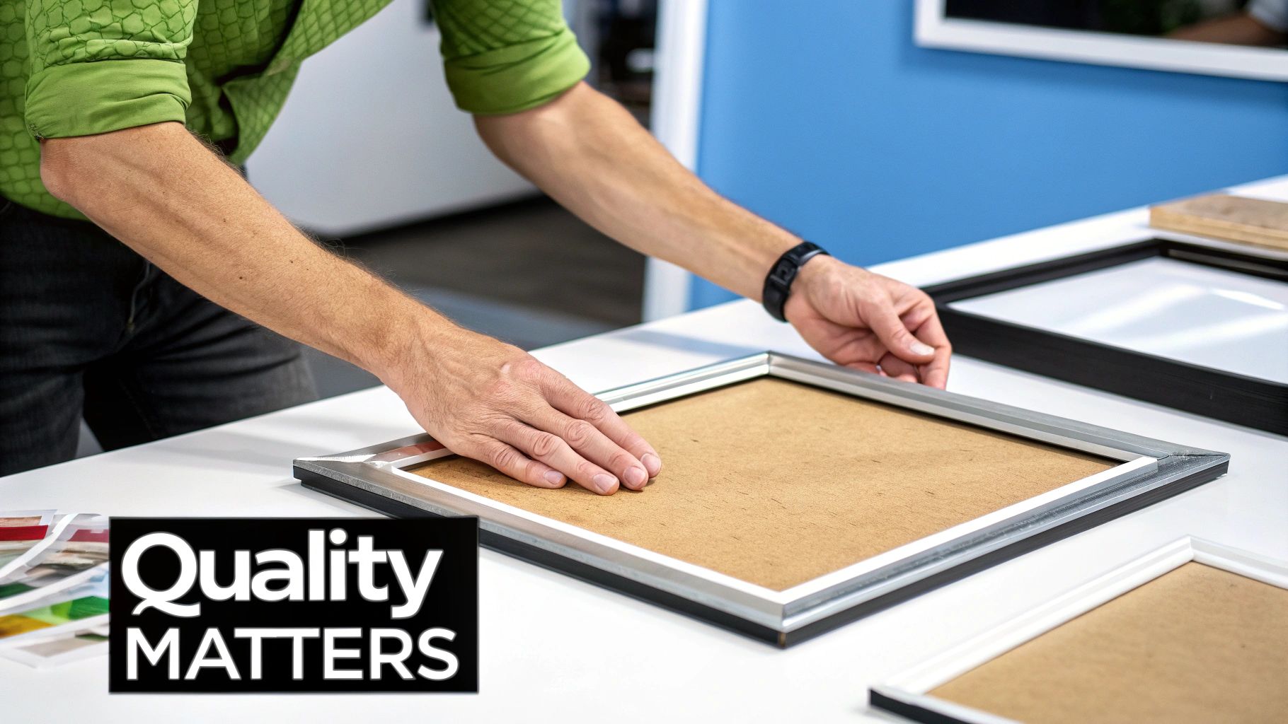 A person's hands carefully assemble a silver picture frame on a white table, with other frames nearby.