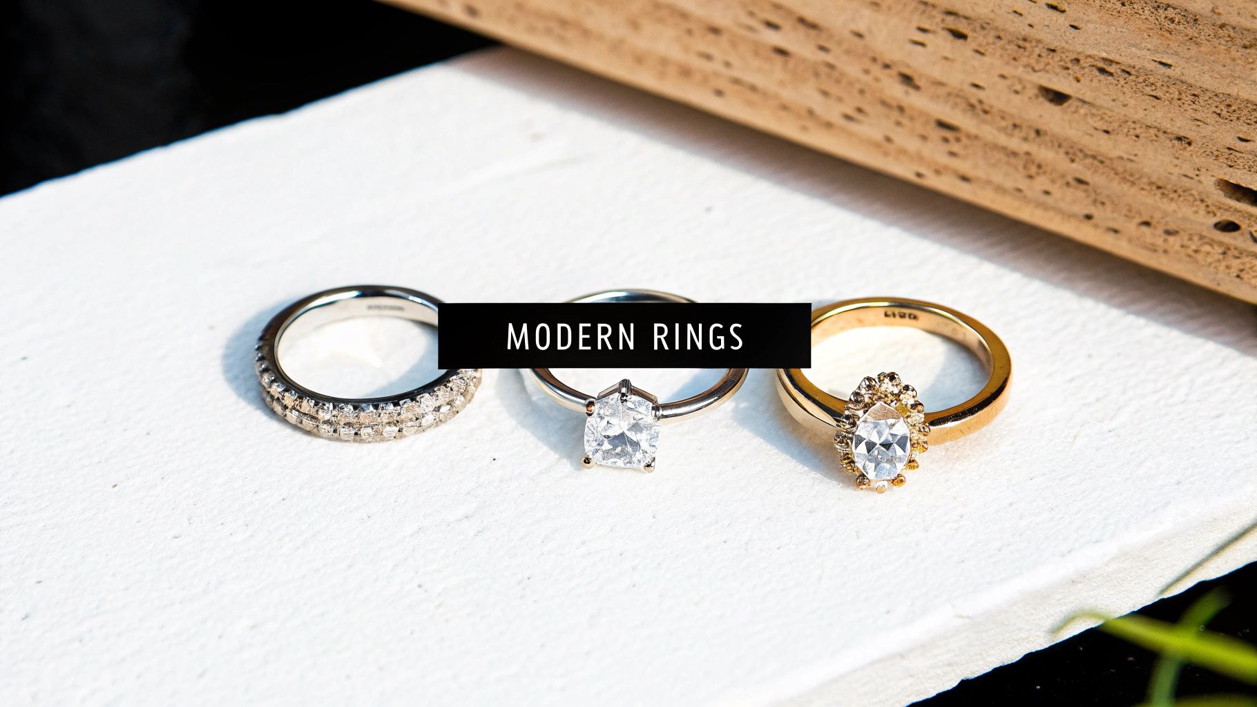 Three modern engagement rings with diamonds displayed on white surface, featuring different metal and stone settings
