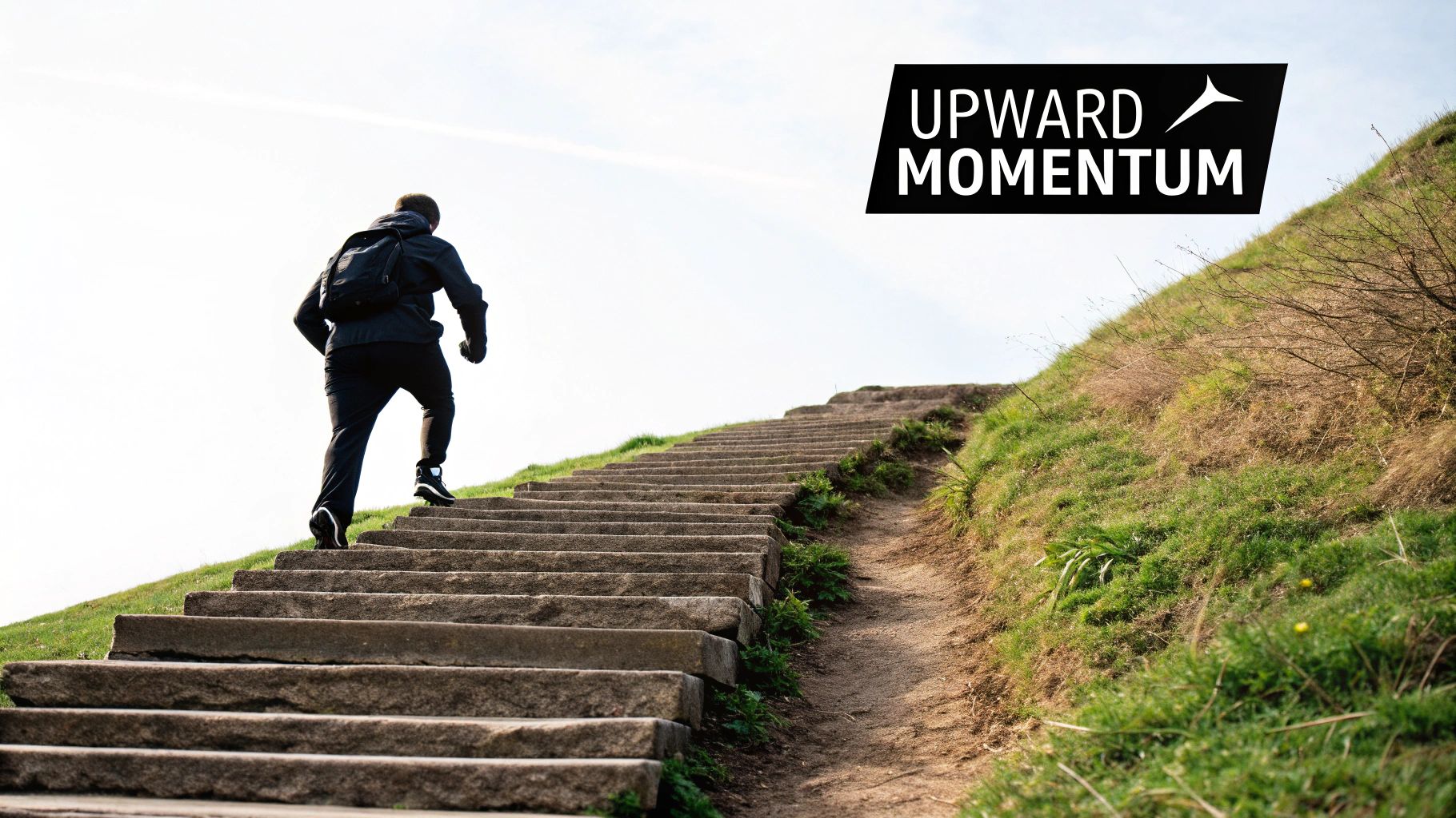 A person with a backpack walks up stone stairs on a grassy hill under a bright sky, symbolizing upward momentum.