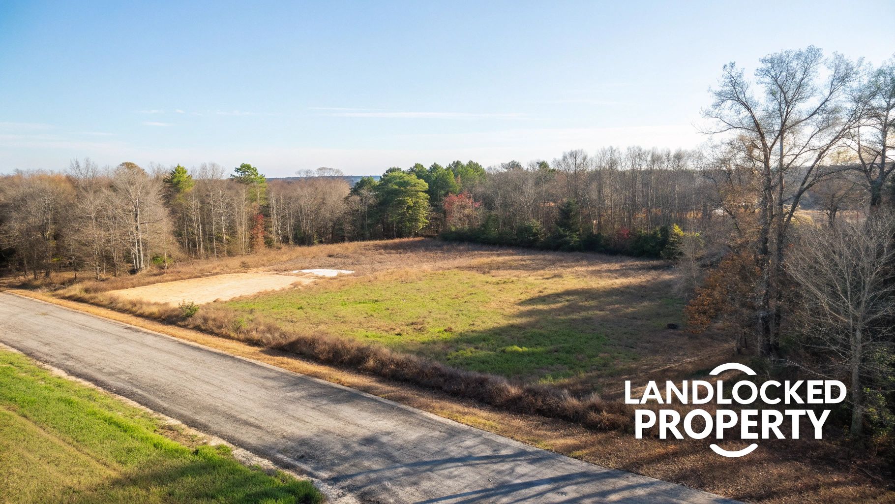 Aerial view of a landlocked property featuring fields, bare trees, and a nearby paved road.