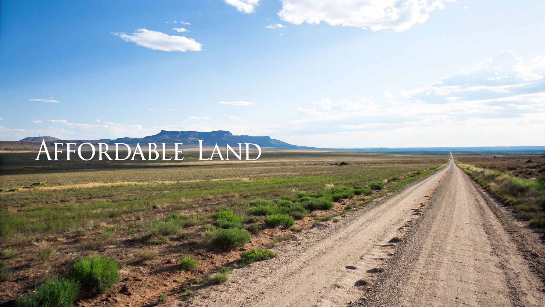 Image showing a long dirt road through vast, affordable land with distant mesas under a bright blue sky.