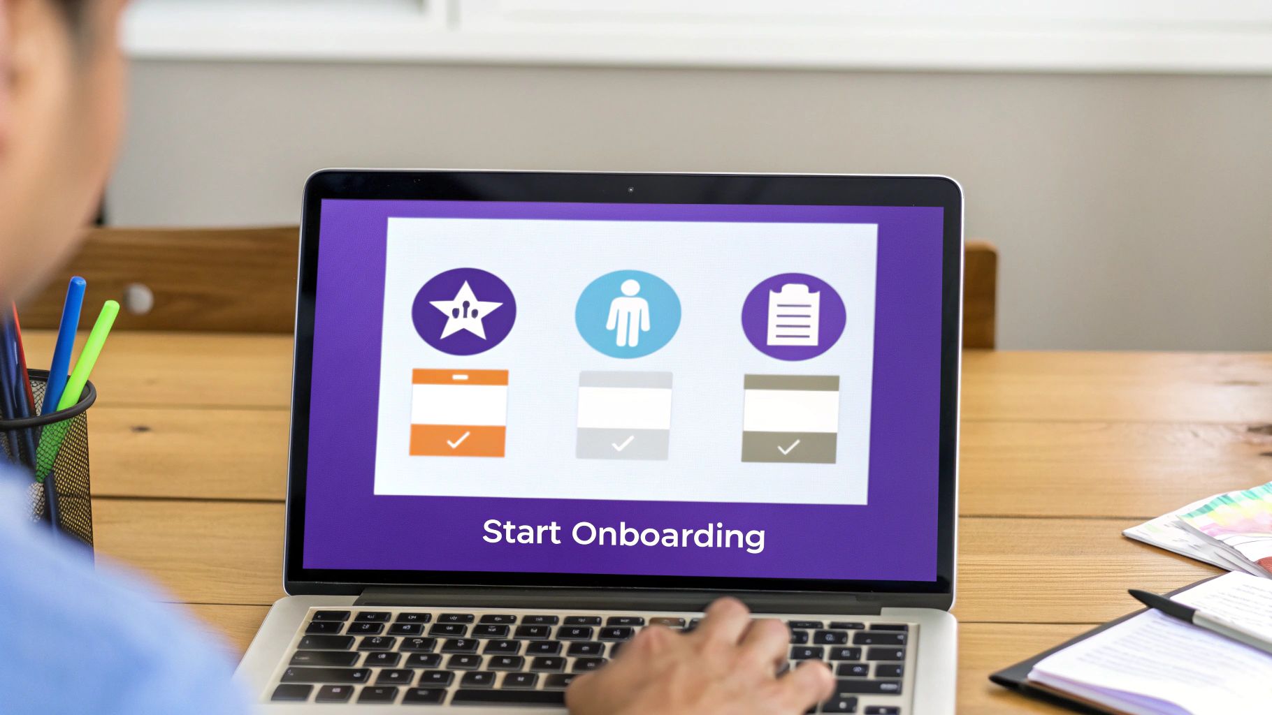 Person engaging with a laptop displaying an 'Onboarding' screen with completed steps and a 'Start Onboarding' button.